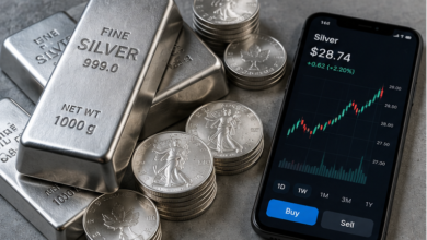 Silver bars and coins beside a phone showing an online trading chart